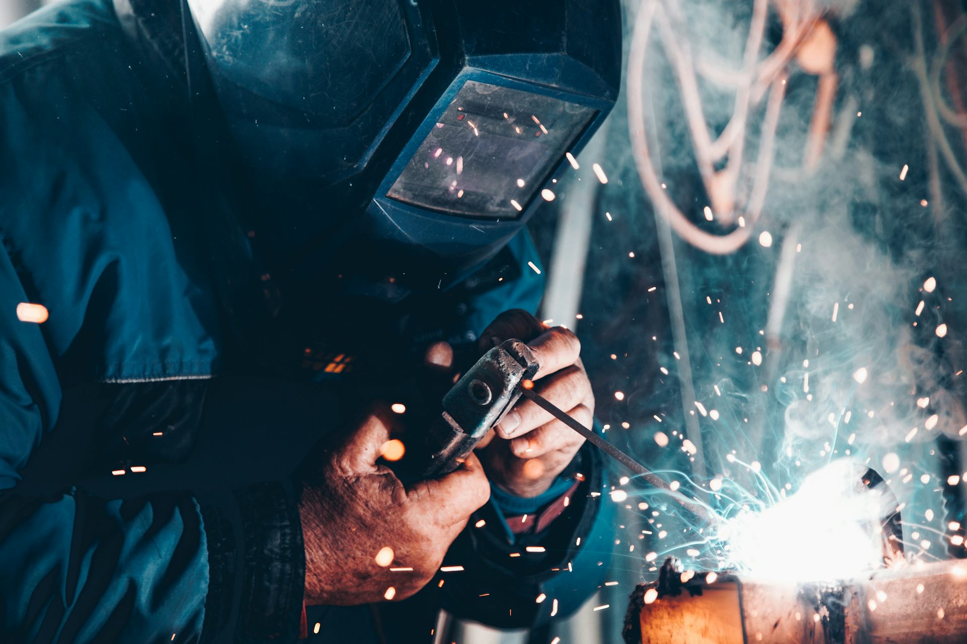 Welder in a protective helmet with blue sparks