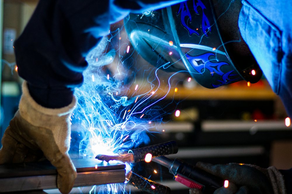 Close-up of a gloved hand welding with blue sparks